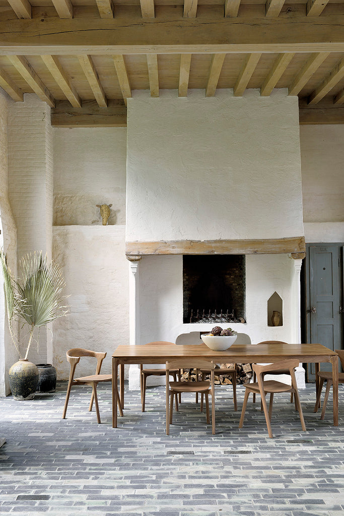 Teak Bok Dining Table and Chairs in European inspired dining room with high ceilings and exposed beams, plaster fireplace and paver floors. - Saffron and Poe, Ethnicraft