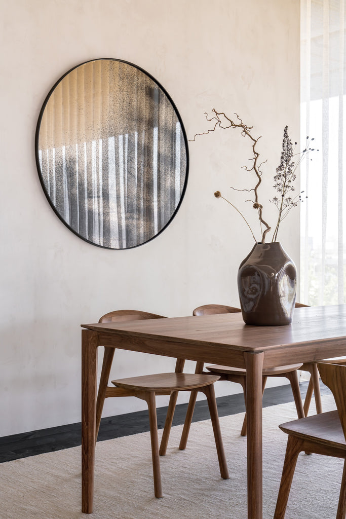 Teak Bok Dining Table in modern dining room with white walls with mirror on wall, black floors and vessel on table. - Saffron and Poe, Ethnicraft