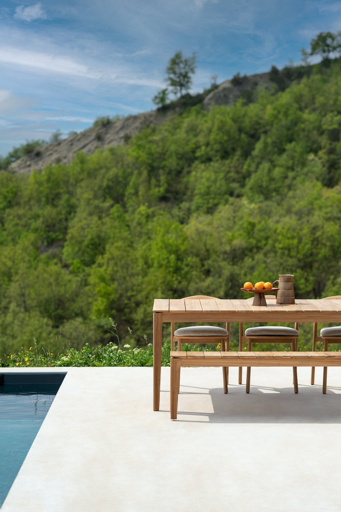 Slatted Teak Bok Outdoor Bench with Teak Bok Outdoor Dining Table next to a modern poolside, styled with a small ceramic bowl and vessel. - Saffron and Poe, Ethnicraft