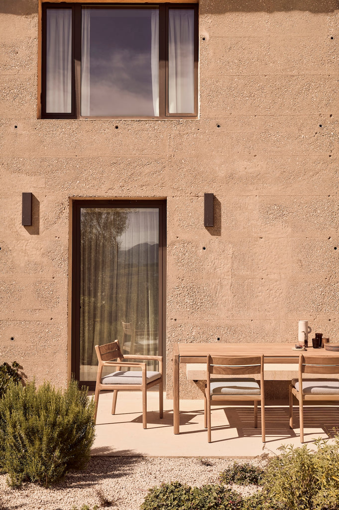 Jack Outdoor Dining Table with Jack Outdoor Dining Chairs on an outdoor patio with modern large windows. - Saffron and Poe, Ethnicraftat
