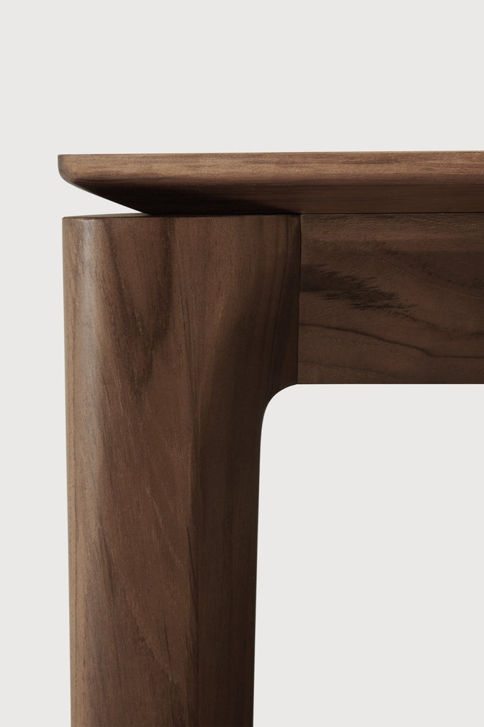 Darkened Teak Bok Dining Table close up side view detail with white background featuring floating table top and beautiful wood joinery. - Saffron and Poe, Ethnicraft