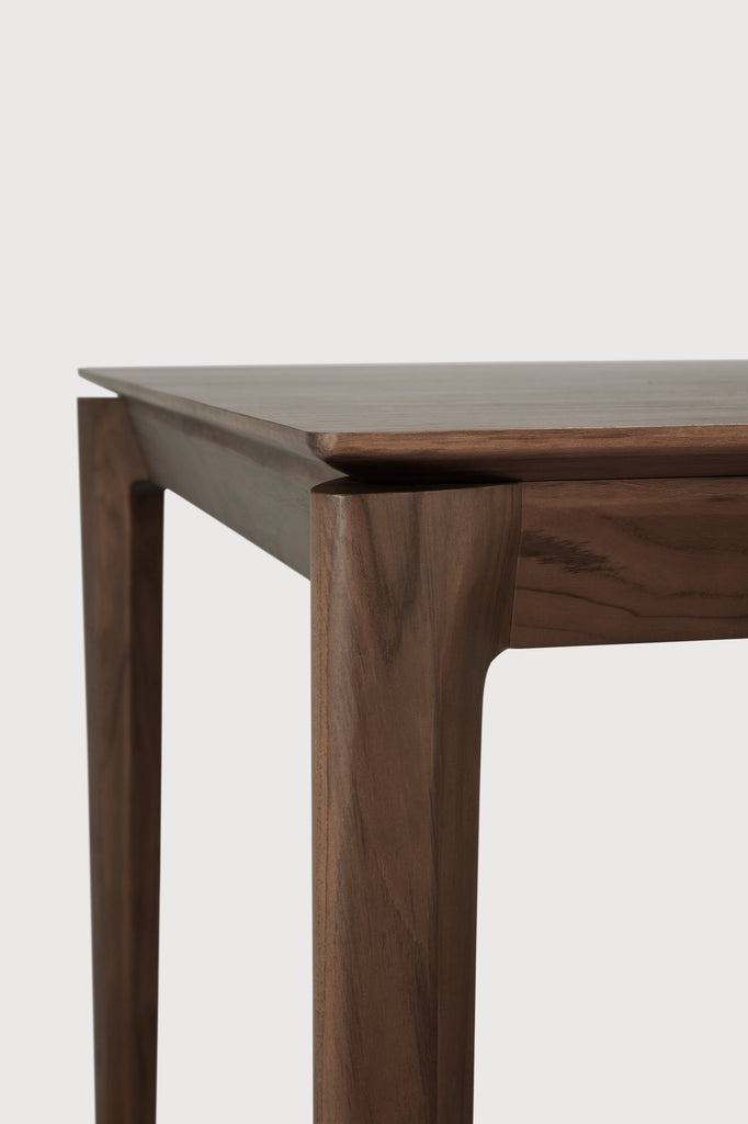 Darkened Teak Bok Dining Table close up detail with white background featuring floating table top and beautiful wood joinery. - Saffron and Poe, Ethnicraft