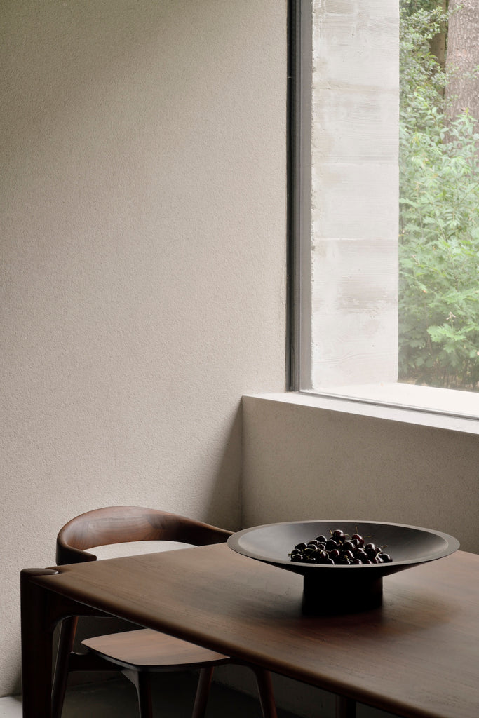 Dark Teak PI Dining Table and Bok Chair in modern concrete and plaster dining room with large windows. - Saffron and Poe, Ethnicraft