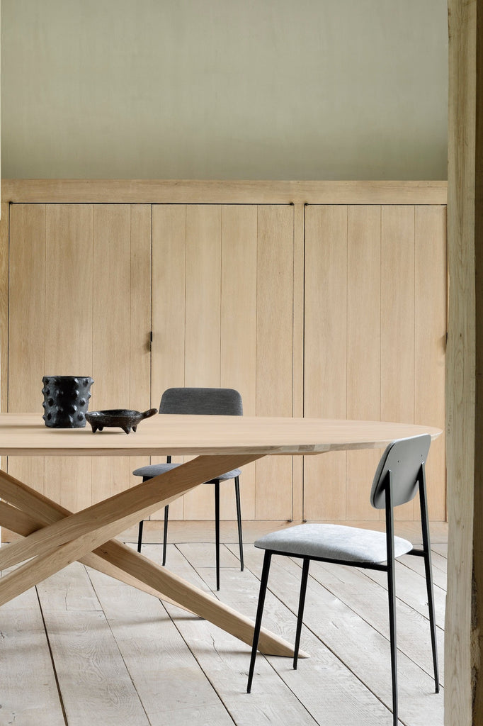 White Oak Oval Mikado Dining Table and in european plastered dining room with exposed rafters and stone fireplace, with objects styled on top. - Saffron and Poe, Ethnicraft