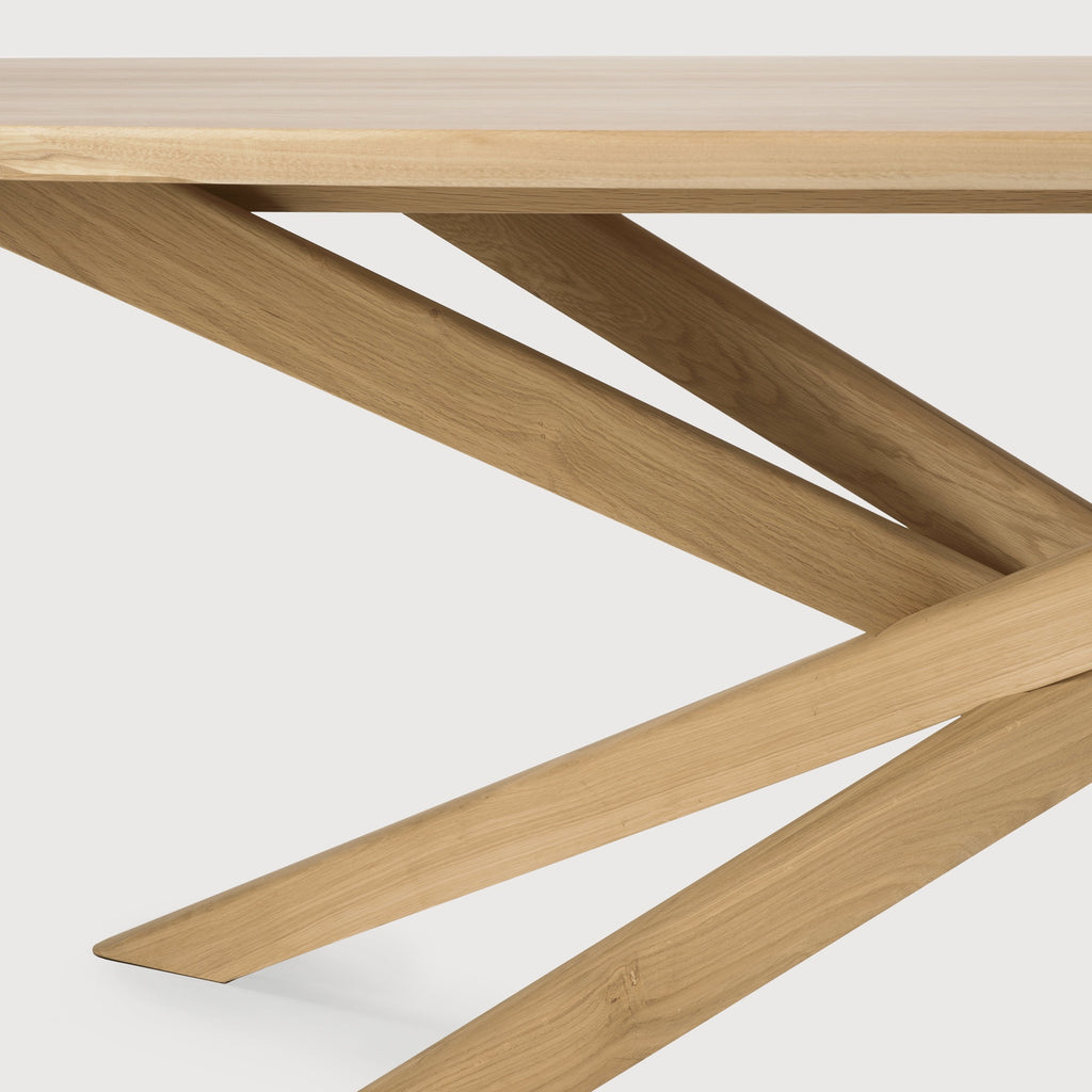 White Oak Oval Mikado Dining Table detail with white background and beautiful intersecting wood legs. - Saffron and Poe, Ethnicraft