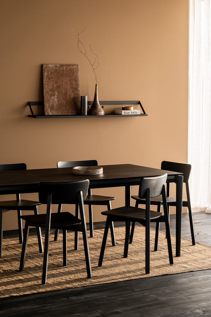 Black Oak Bok Dining Table and chairs in dining room with warm rust walls, sheer curtains on window, jute rug and black wood floors, showing floating wood table top. - Saffron and Poe, Ethnicraft