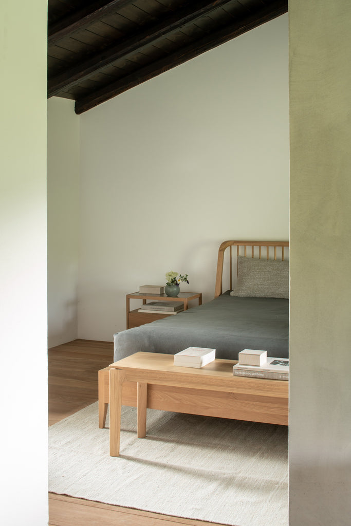 White Oak Spindle Bed angle view vignette in bedroom with exposed beam ceiling and White Oak Bok Bench. - Saffron and Poe, Ethnicraft