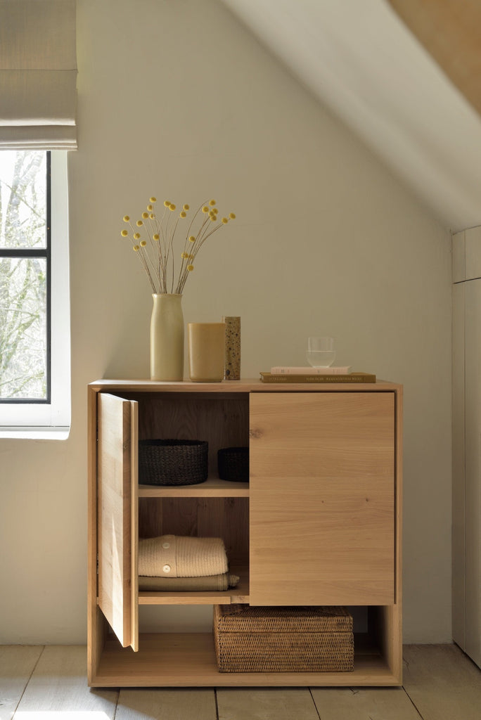 White Oak 2 door Nordic Sideboard Console in plastered modern bedroom with slanted ceilings, antique wood flooring, with door open showing clothing and baskets. - Saffron and Poe, Ethnicraft