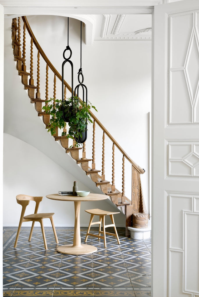 Teak Bok Dining Chairs with round table in European Entryway with intricate curved stairway and beautiful antique tile. - Saffron and Poe, Ethnicraft