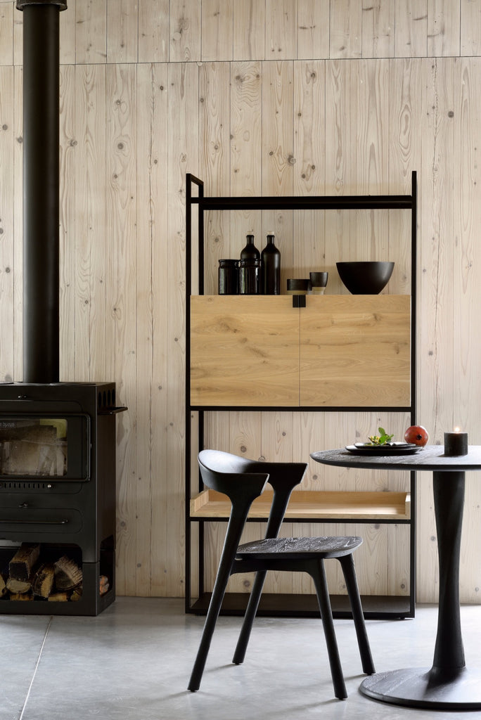 Black Oak Bok Chair in cozy modern European dining room with fireplace, wood paneled walls and concrete floors. - Saffron and Poe, Ethnicraft