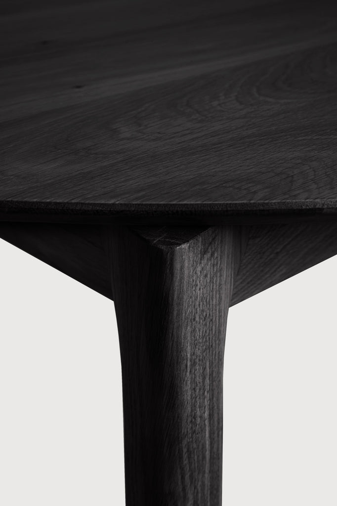 Black Oak Bok Round Extendable Dining Table close up detail of top and leg with white background featuring floating table top and beautiful wood joinery. - Saffron and Poe, Ethnicraft