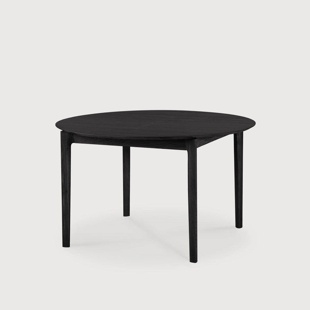 Black Oak Bok Round Extendable Dining Table with white background at an angle in closed position, with floating table top and beautiful wood joinery. - Saffron and Poe, Ethnicraft