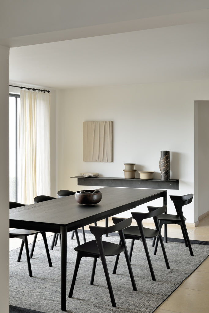 Black Oak Bok Dining Table and Black Oak Bok chairs in dining room with white walls with modern art, sheer curtains on window, area rug and wood floors, showing floating wood table top. - Saffron and Poe, Ethnicraft