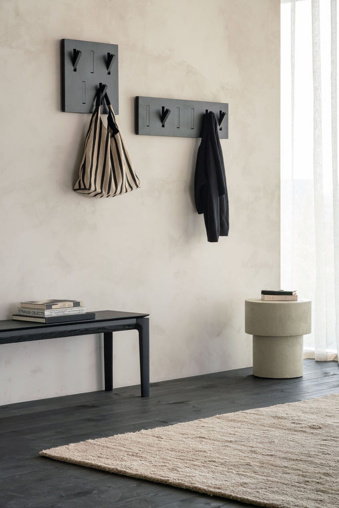 Black Oak Bok Bench in entryway with modern art and a kilim rug, styled with objects on it. - Saffron and Poe, Ethnicraft