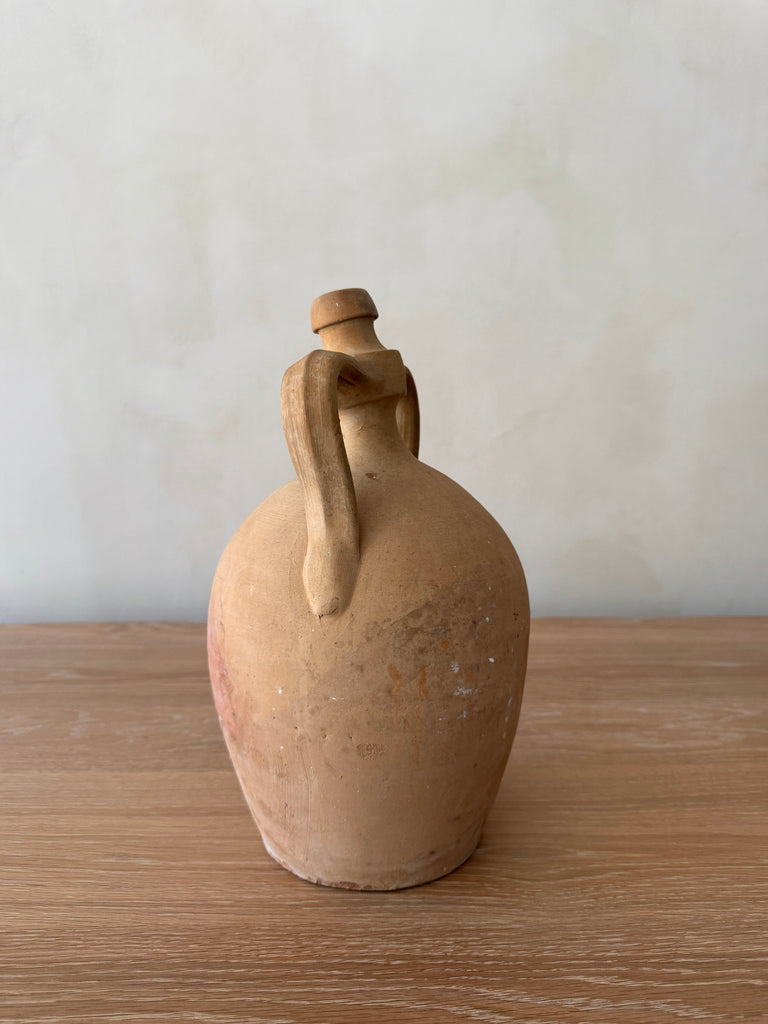 Antique Italian Vessel with handles on a wooden surface and neutral lime washed background. Saffron + Poe