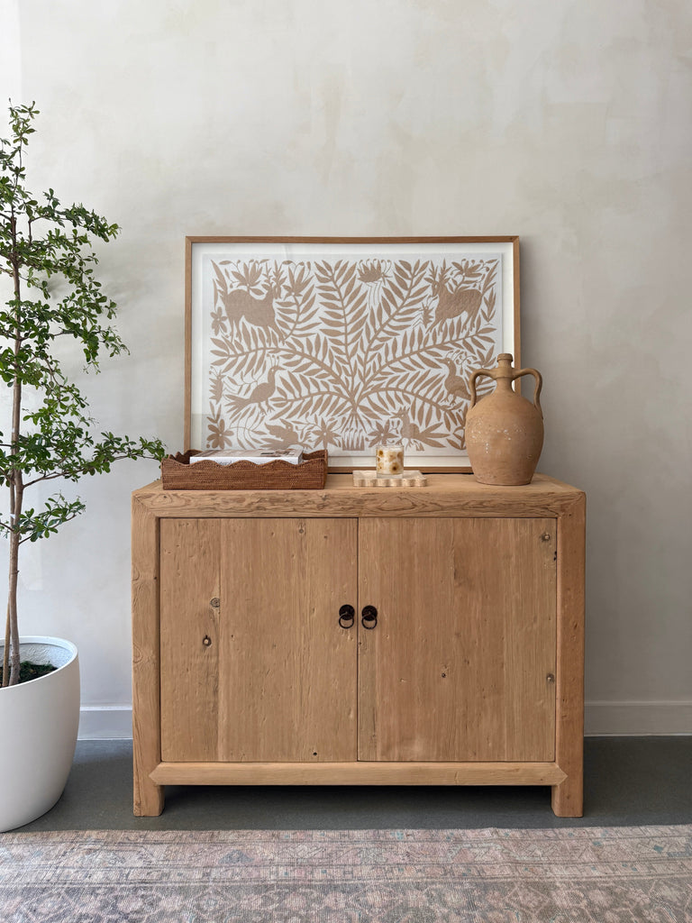 Antique Italian Vessel with handles on a wooden cabinet against a neutral lime washed background. Saffron + Poe