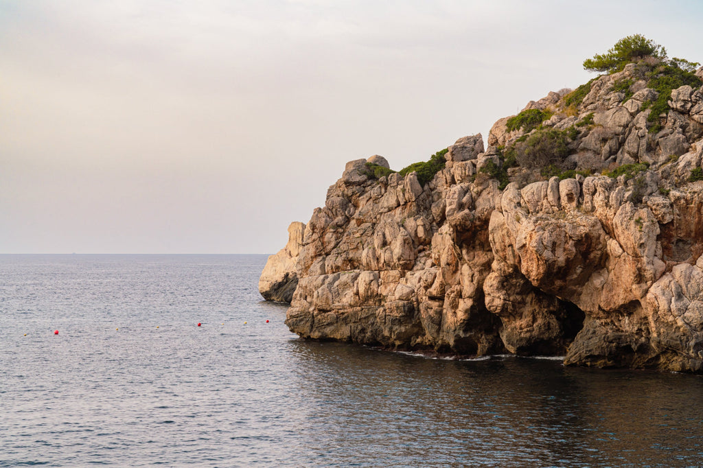 Photo of rocky cliffs at oceans edge by Mika Street for Saffron and Poe