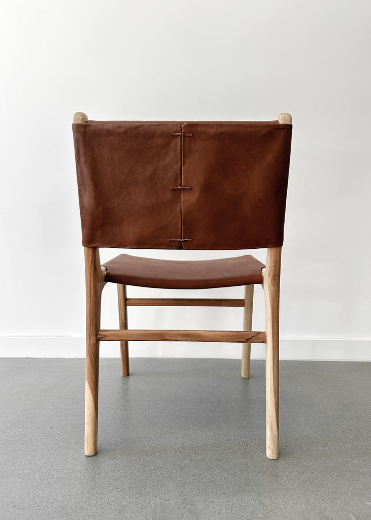 Back of our Stretched Leather and Teak Wood Sofía Dining Chair with leather ties shot against a white background. - Saffron + Poe