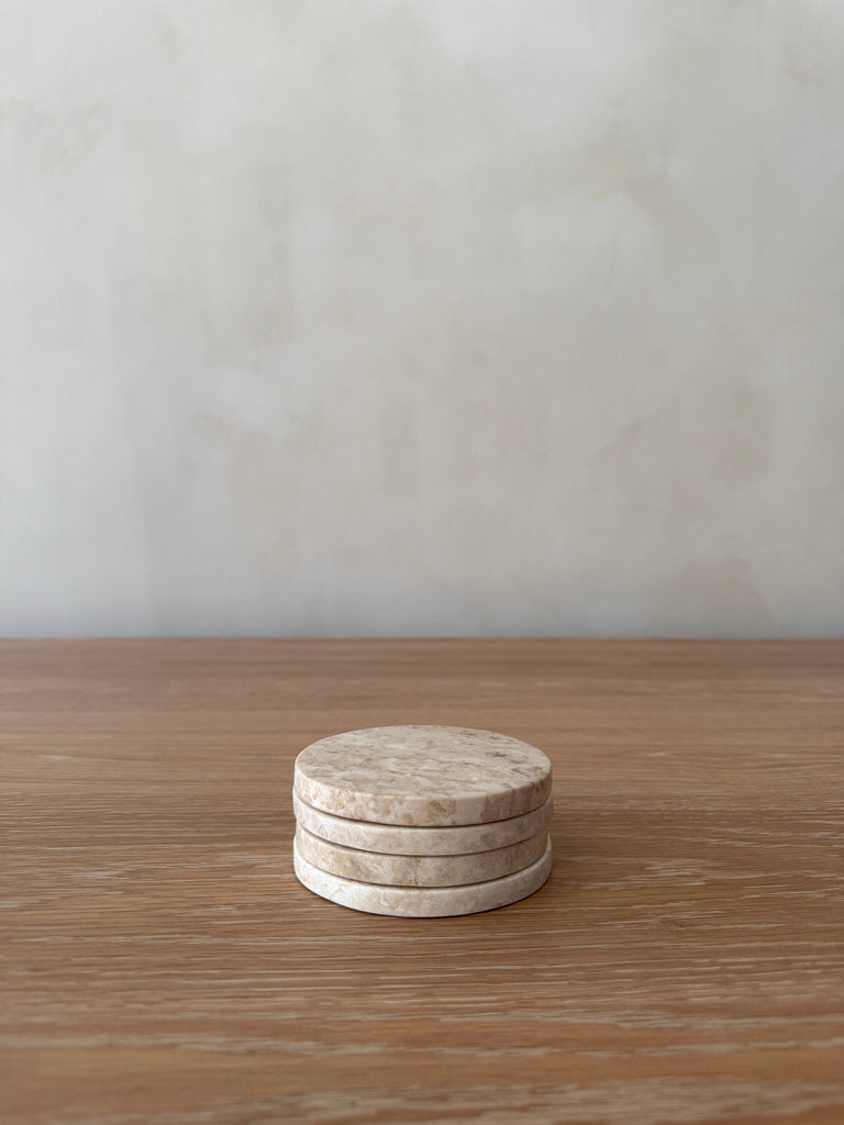 Stack of round stone coasters on a wooden surface with a plain background