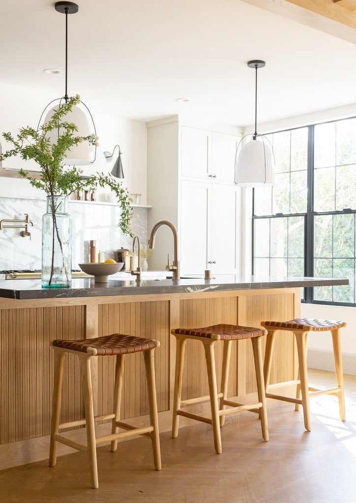 Styled Backless Woven Leather Counter Stool - Saddle in an open and bright kitchen. - Saffron and Poe