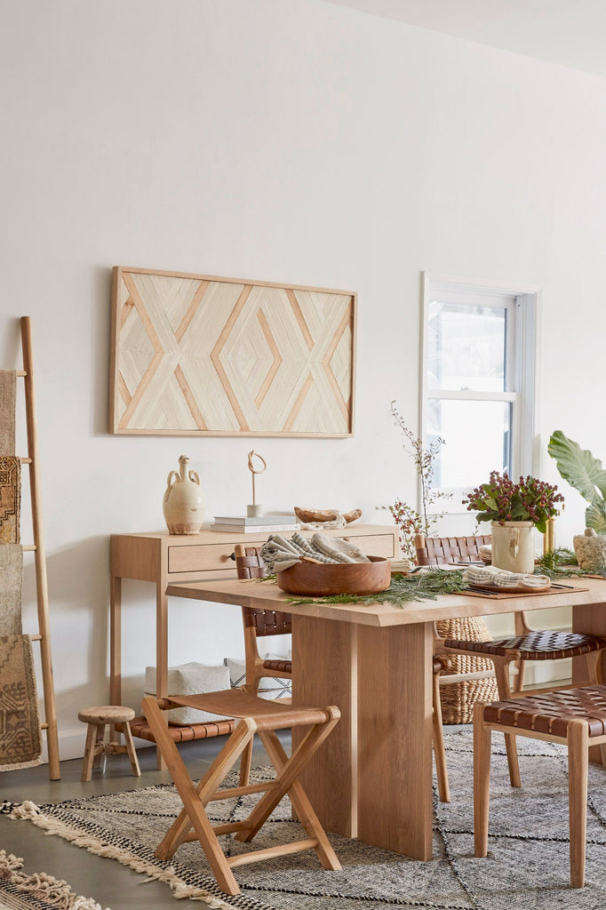 Leather Folding Stool styled in a dining room setting with Live Edge Oak Dining Table, Woven Leather Bench, Teak Salad Bowl, Moroccan Rug, and Oak Console Table. - Saffron and Poe