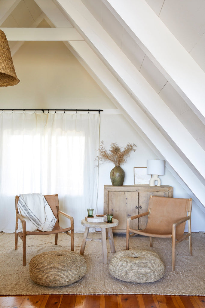 Leather Sling Lounge Chairs styled in a sitting room with natural poufs, round vintage end table, and Mijiu Jar. - Saffron and Poe