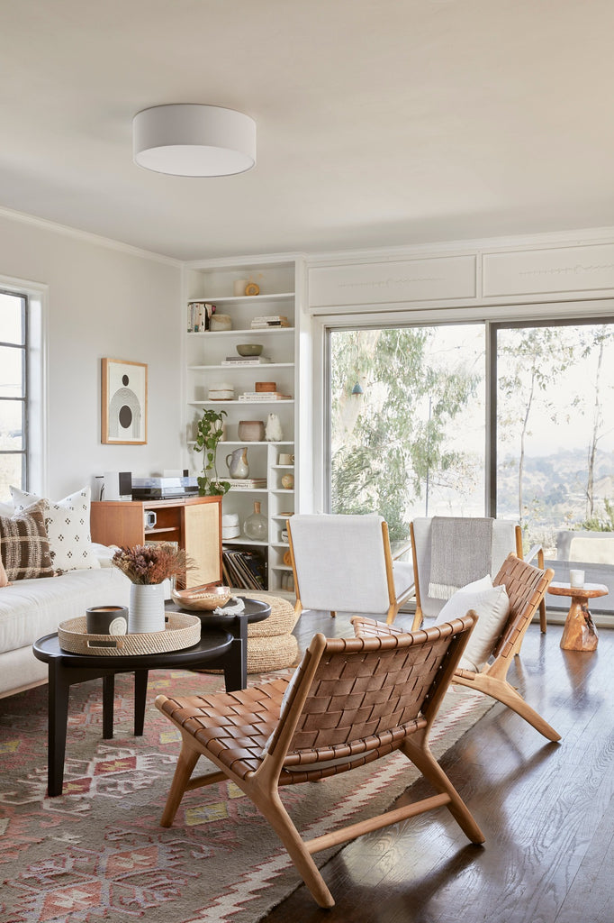 Woven Leather Lounge Chair styled in a living room setting with Natural Poufs, Ceramic Vase, Brown Checkered Pillow, and Bhujodi Pillow. - Saffron and Poe