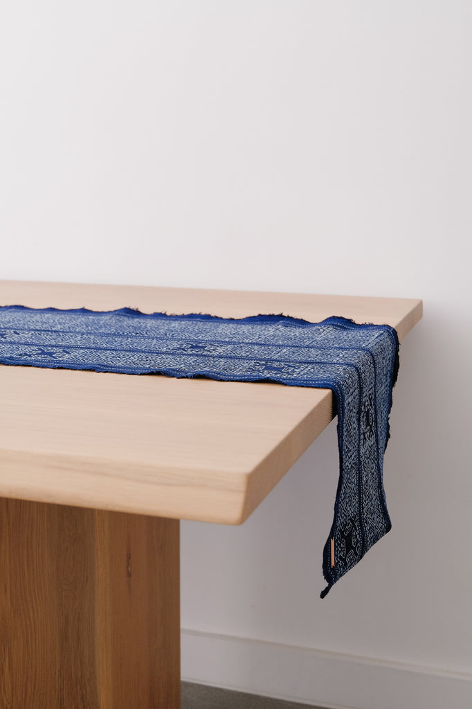 Angled view of Hmong Batik Table Runner on an Oak Dining Table. - Saffron and poe