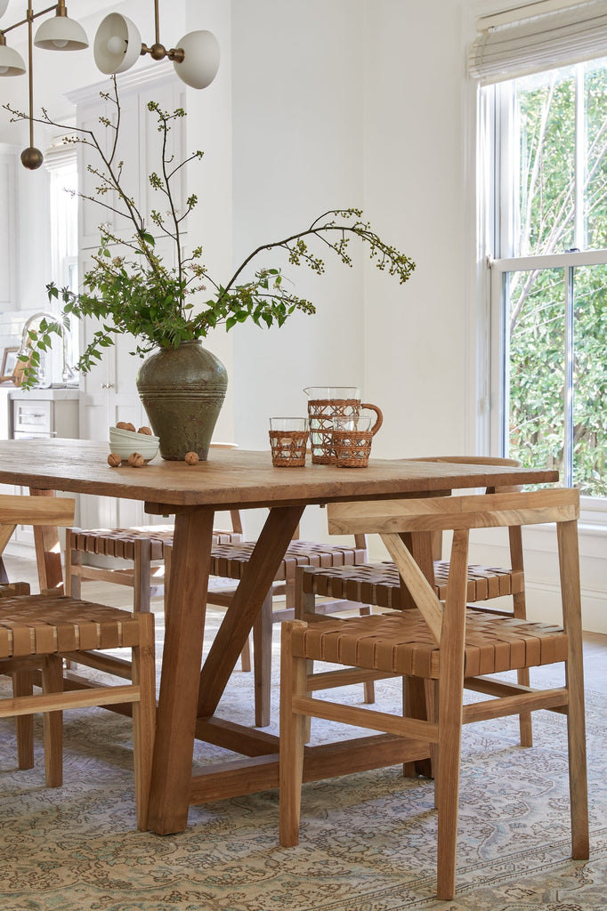Angled view of styled photo with Vintage Mijiu Jar on top of oak table with Woven Leather Wishbone Dining Chairs. -Saffron and Poe