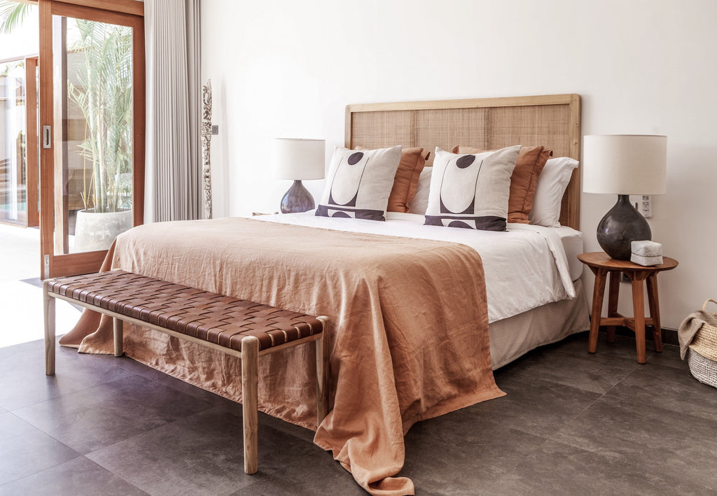 Side angle view of our Teak framed Woven Leather Strap Bench styled at bottom of bed in bohemian bedroom. Furniture Handcrafted in Bali.- Saffron and Poe