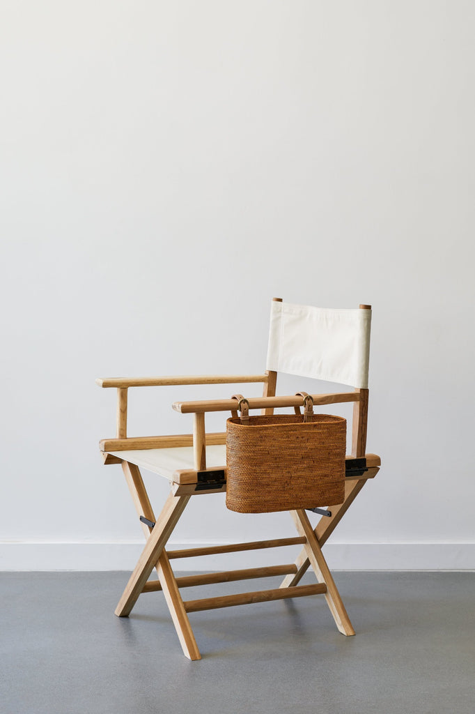 Side view of Canvas Director's Chair in Oatmeal with Tenganan Side Basket against a white background and concrete flooring. - Saffron and Poe