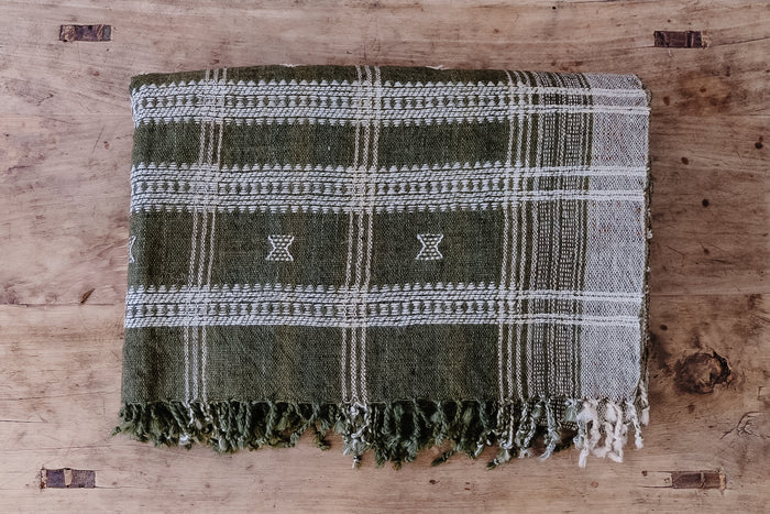 Front view of Handwoven Bhujodi Blanket - Green on an Antique Chinese Coffee Table. - Saffron and Poe