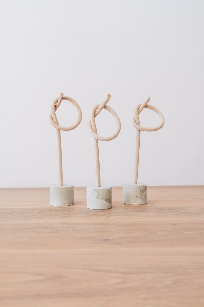 Front view of three Katie Kong Small Wood Knot Sculptures on an Oak Dining Table against a white wall. - Saffron and Poe