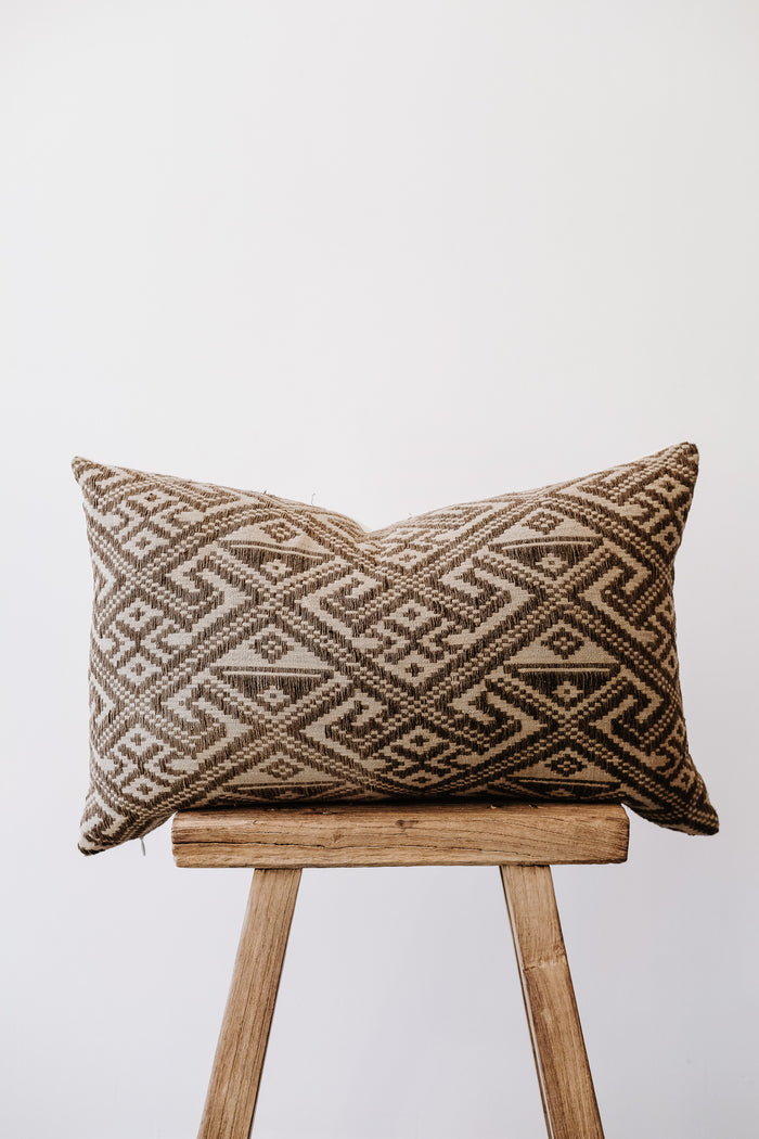 Front view of No. 25 - Antique Miao Lumbar Pillow on an Antique Stool against a white wall. - Saffron and Poe