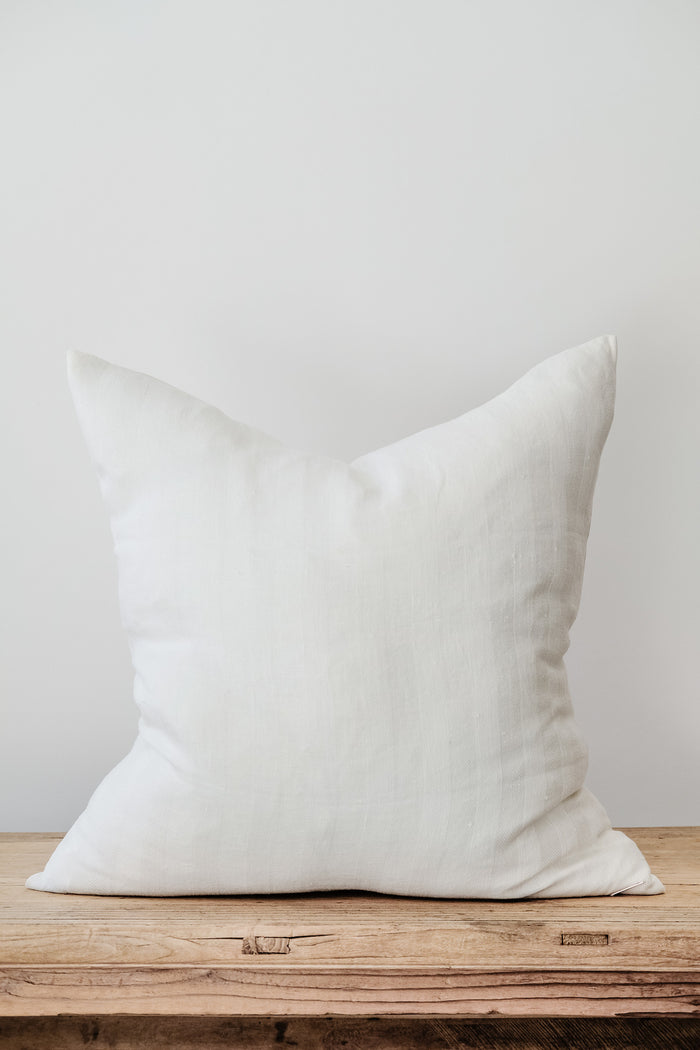 Front view of No. 51 - Ivory Linen Pillow on an Antique Bench against a white wall. - Saffron and Poe