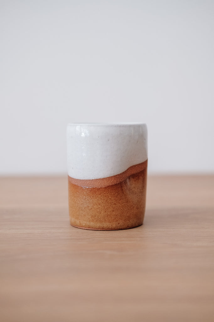 Front view slightly turned of Uzumati Drifter Tumbler on a White Oak Table against a white wall. - Saffron and Poe