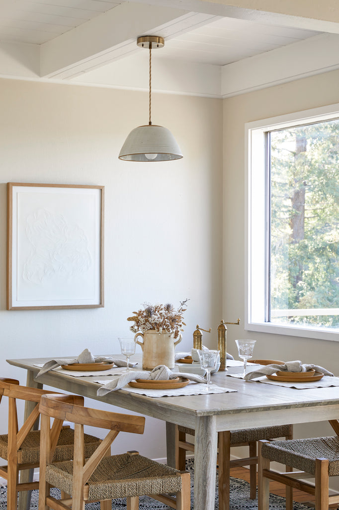 Styled Natural Linen Placemat with Uzumati Ceramic Plates, Natural Linen Napkins, an Italian Confit Pot, Atlas Brass Grinders, and a Hand Thrown Ceramic Pendant Lamp. - Saffron and Poe