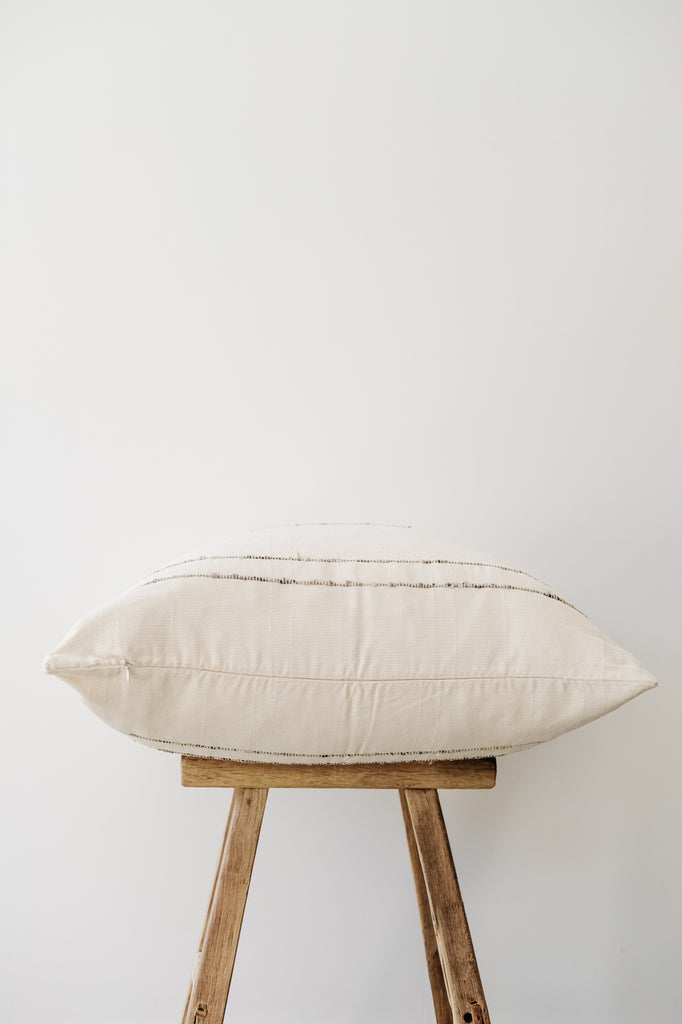 Side view of No. 48 - Azulina - Ivory with Grey Stripe Handwoven Columbian Pillow on a Chinese Stool against a white wall. - Saffron and Poe