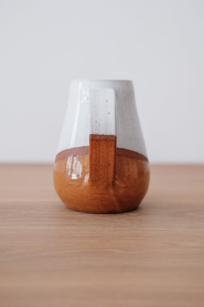 Side view of Uzumati Drifter Pitcher on a White Oak Table against a white wall. - Saffron and Poe