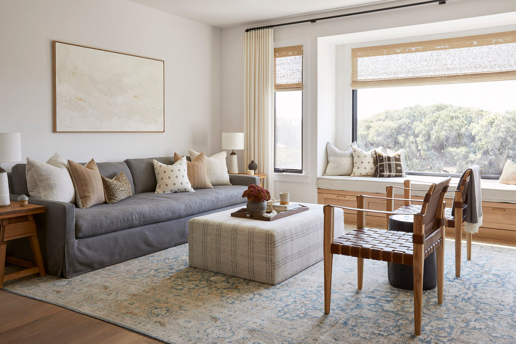 Styled Ivory Handwoven Columbian Pillow with Beige Embroidered Pillow and Brown Checkered Pillow in a neutral living room with a Vintage Cedar End Table and Leather Strap Safari Chairs. - Saffron and Poe