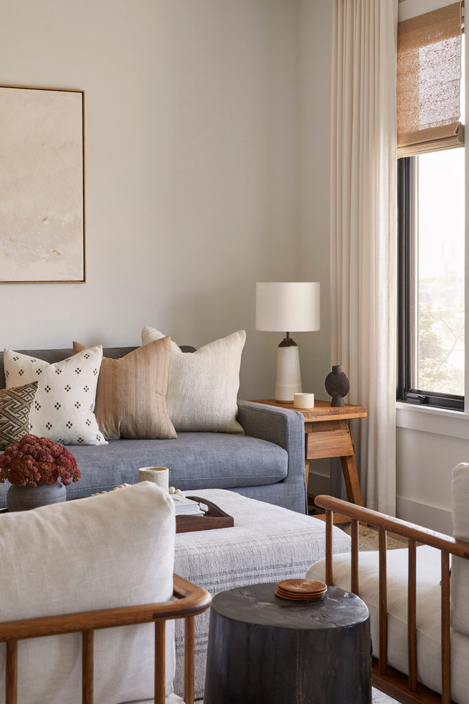 Styled Ivory Handwoven Columbian Pillow with Beige Embroidered Pillow and Brown Checkered Pillow in a neutral living room with a Vintage Cedar End Table. - Saffron and Poe