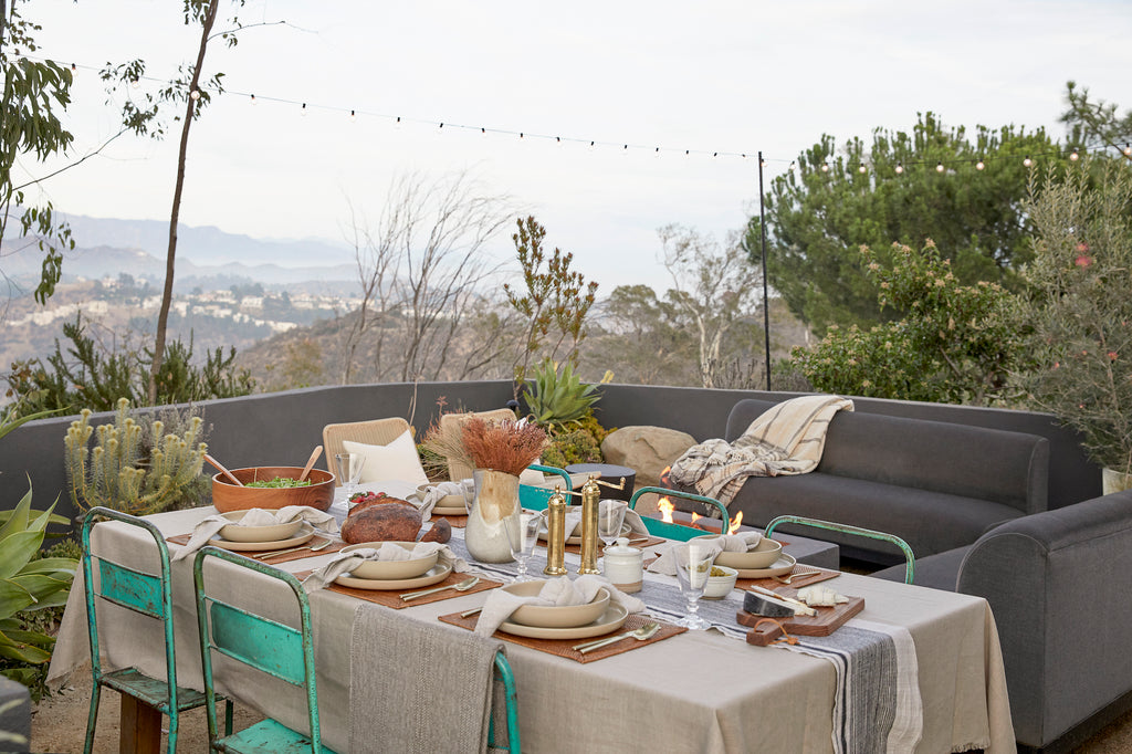 Styled Natural Linen Napkin on a Tengnanan Placemat with Brass Grinders, Hand Thrown Ceramics, a Teak Salad Bowl, a Pair of Wooden Tongs, a Studio Inko Cutting Board and a Hmong Table Runner. - Saffron and Poe