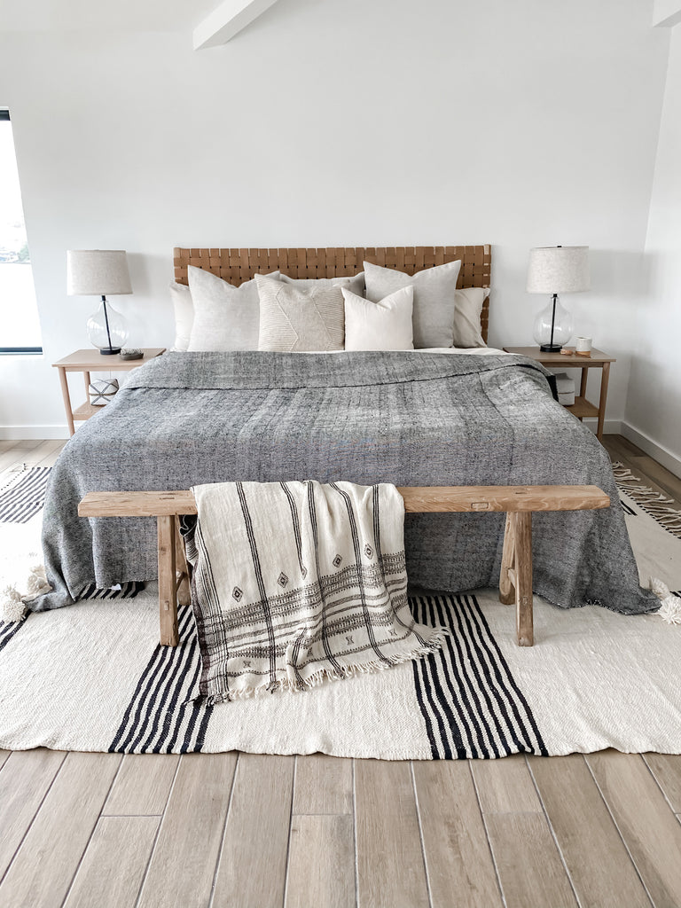 Styled Natural Linen Pillow with a Woven Leather Strap Headboard and an Antique Chinese Bench and a Bhujodi Blanket on a Turkish Kilim Rug. - Saffron and Poe