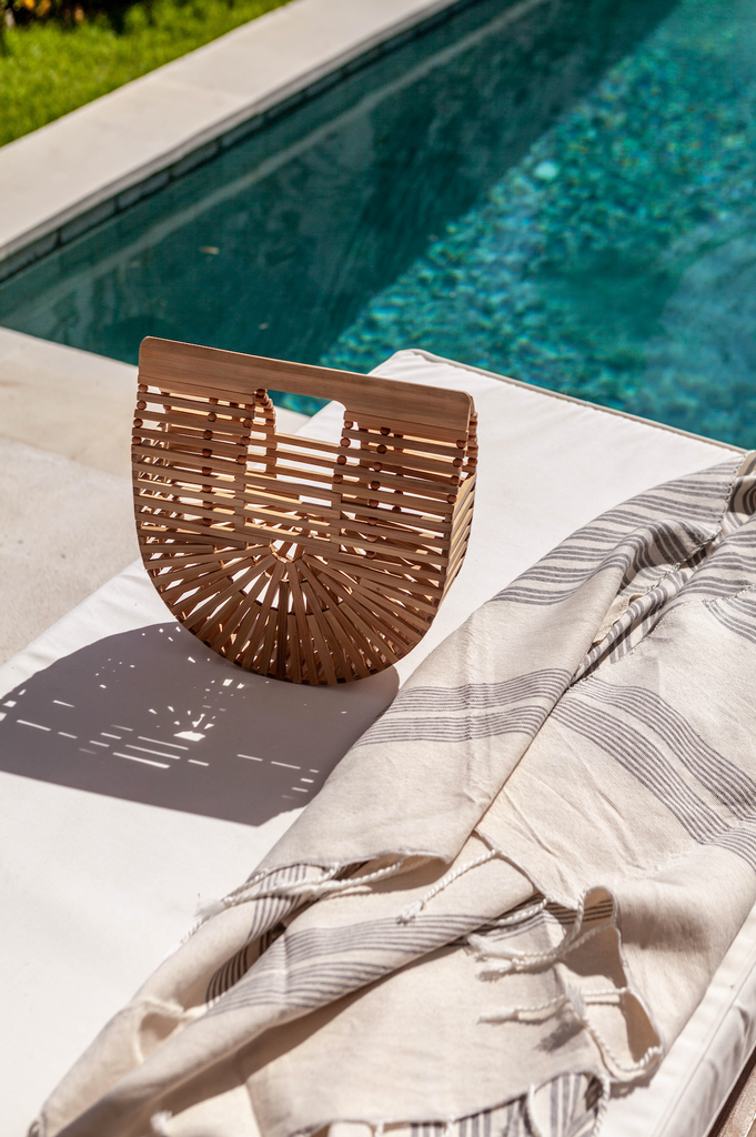 Bamboo Crescent Clutch boho bag styled at the pool with towel. Handcrafted in Bali with bamboo. - Saffron and Poe