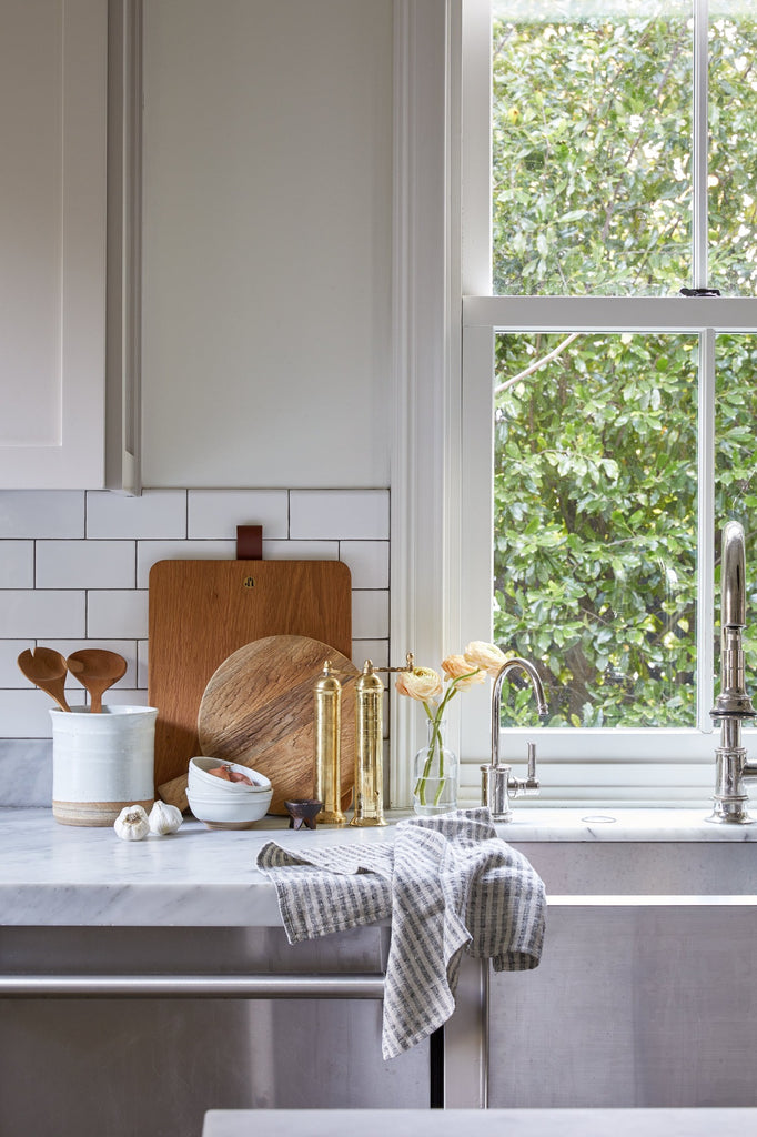 Blue/Grey Stripe Linen Hand Towel styled in a kitchen with Atlas Brass Salt Grinder,  Altas Pepper Grinder, Ceramic Salt Bowl, Ceramic Utensil Jar, and Studio Inko Serving Board. - Saffron and Poe