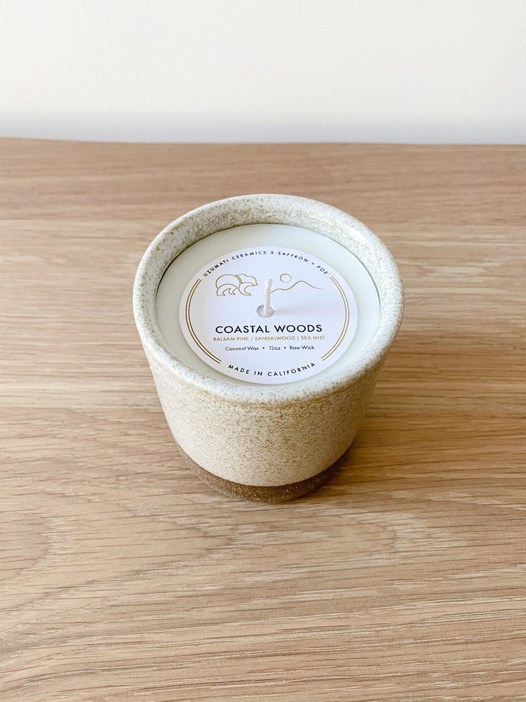Top view of Uzumati Coastal Woods Candle on white oak against a white wall - Saffron and Poe