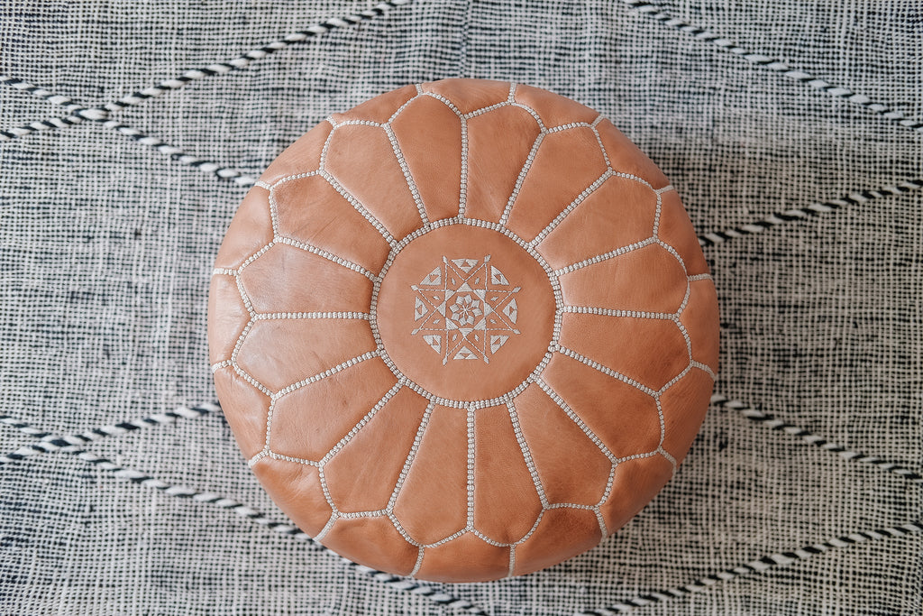 Top view of Embroidered Leather Moroccan Pouf on a Moroccan Kilim Rug. - Saffron and Poe