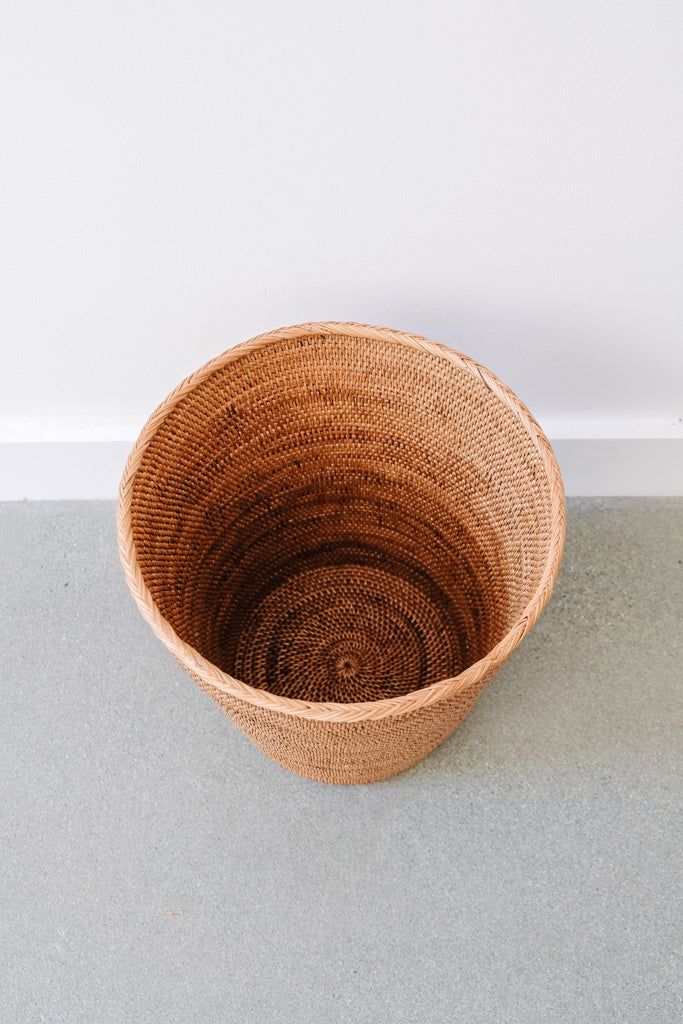 Top view of Woven Tenganan Waste Basket against a white wall. - Saffron and Poe