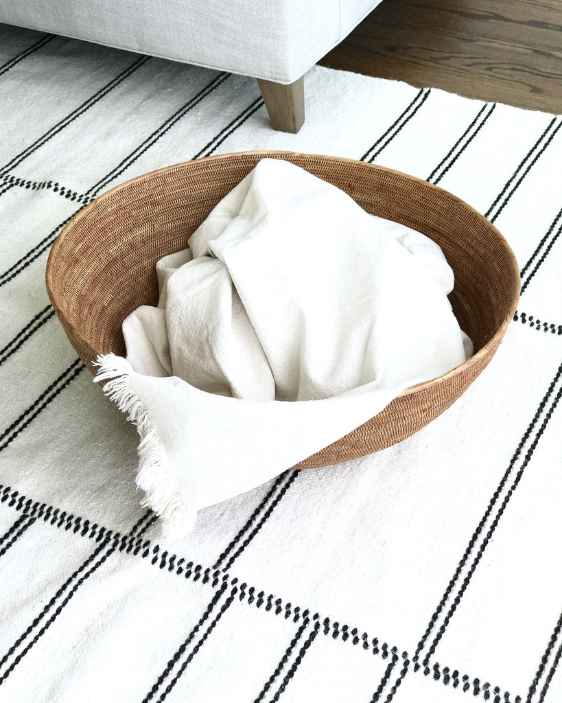 One Woven Tenganan accent storage basket with a blanket. Handwoven in Tenganan, Bali using Ata reed on a white background. - Saffron and Poe