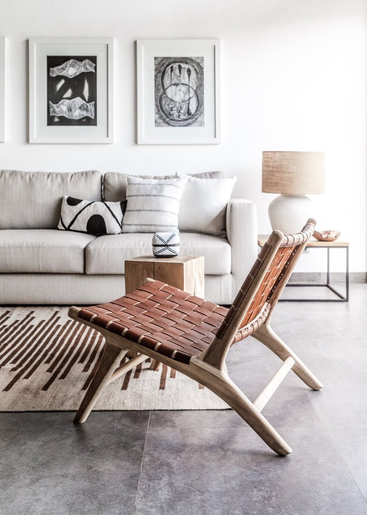 Side angle view of our Woven Leather Strap Lounge Chair in Saddle styled in a white, open living room. Handmade in Bali with Teak wood and vegetable-tanned leather imported from Java. - Saffron and Poe